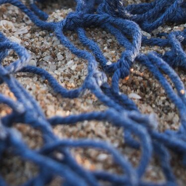 Plastikmüll in einem Fischernetz am Strand Plastikmüll in einem Fischernetz am Strand
